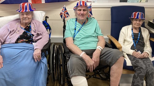 Three patients at the Cumberlege Intermediate Care Centre wearing Union Jack hats at a coronation tea party held at the centre
