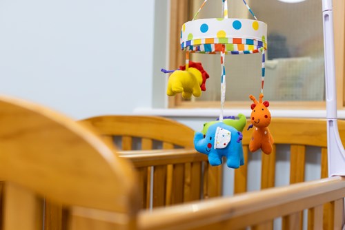 A baby's cot with a mobile above featuring a soft toy lion, elephant and giraff