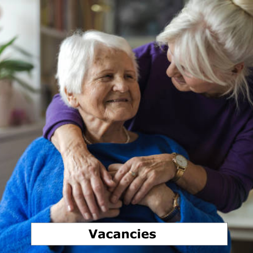 Two older ladies in a hug holding hands.