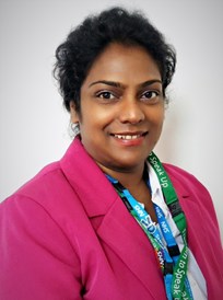 Yogeeta Mohur,smiling, brown skinned woman with black hair. Wearing a pink blazer and white shirt.