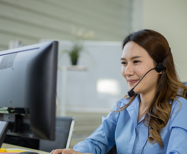 Woman wearing headphones with a microphone sitting in front of a computer