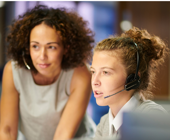 Two women looking at something, both are wearing a headphone with microphones